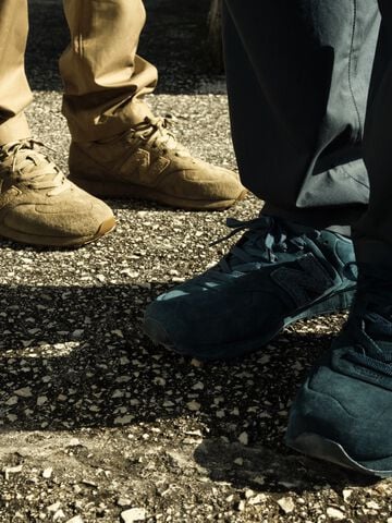 Blue and beige Stone Island and New Balance 574 Ghost leather trainers worn outdoors, close-up view